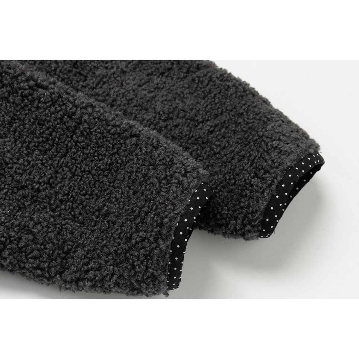 Close-up of charcoal nubby fabric edges finished with black binding dotted in white.