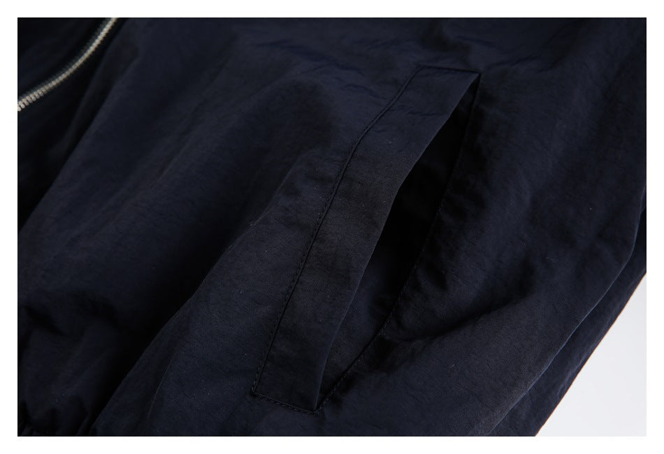 Close-up of a dark navy jacket pocket opening and adjacent zipper edge.