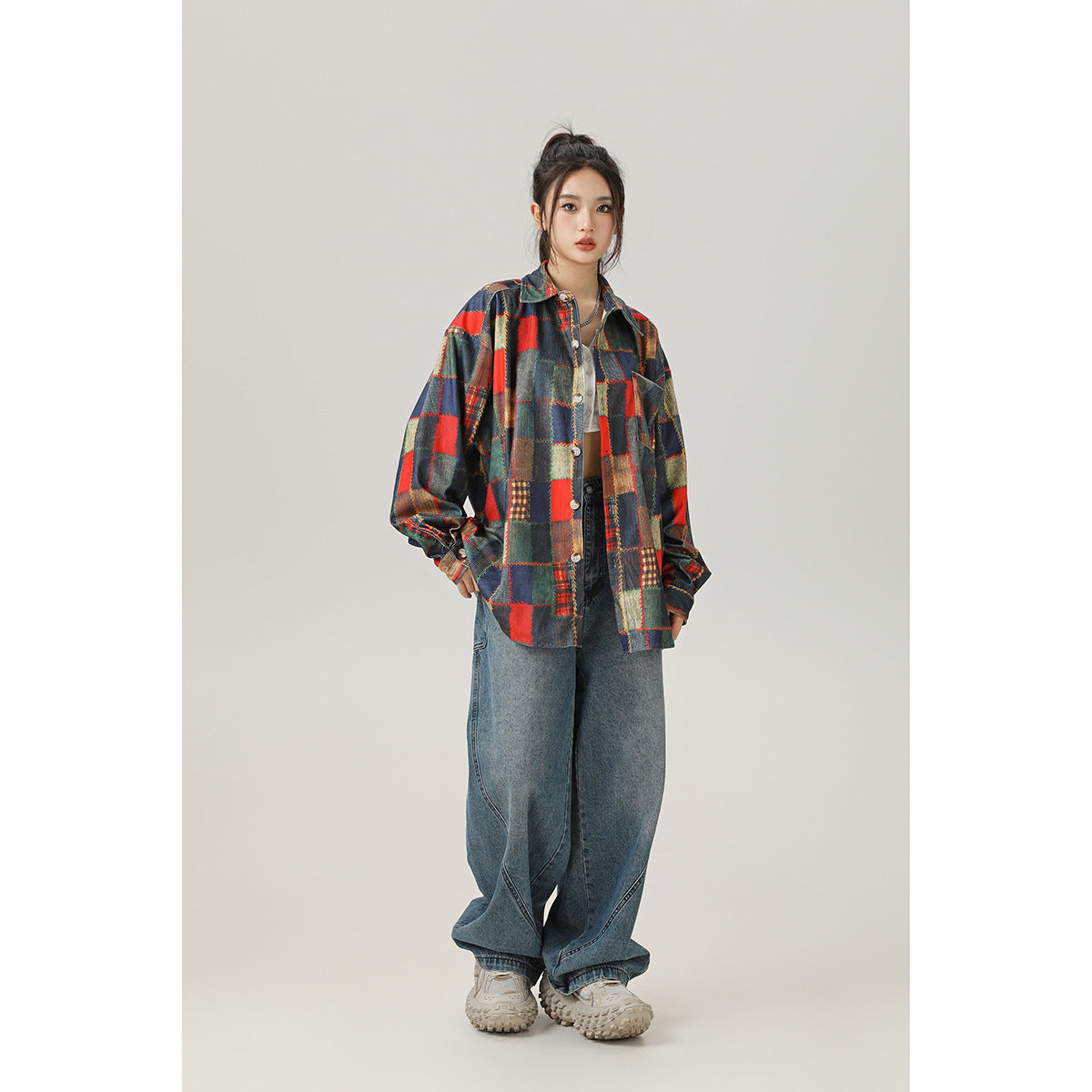 Full-length front view of a model in a multicolor patchwork plaid shirt, wide-leg jeans, and sneakers.