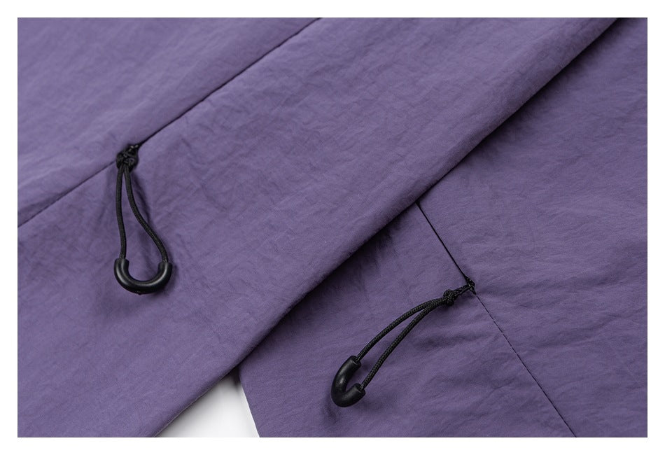 Close-up of purple pants with black cord loops and toggle adjusters at stitched seams.