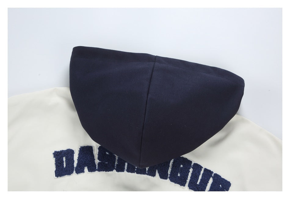 Close-up of a navy hood resting over a white garment with partially visible navy lettering.