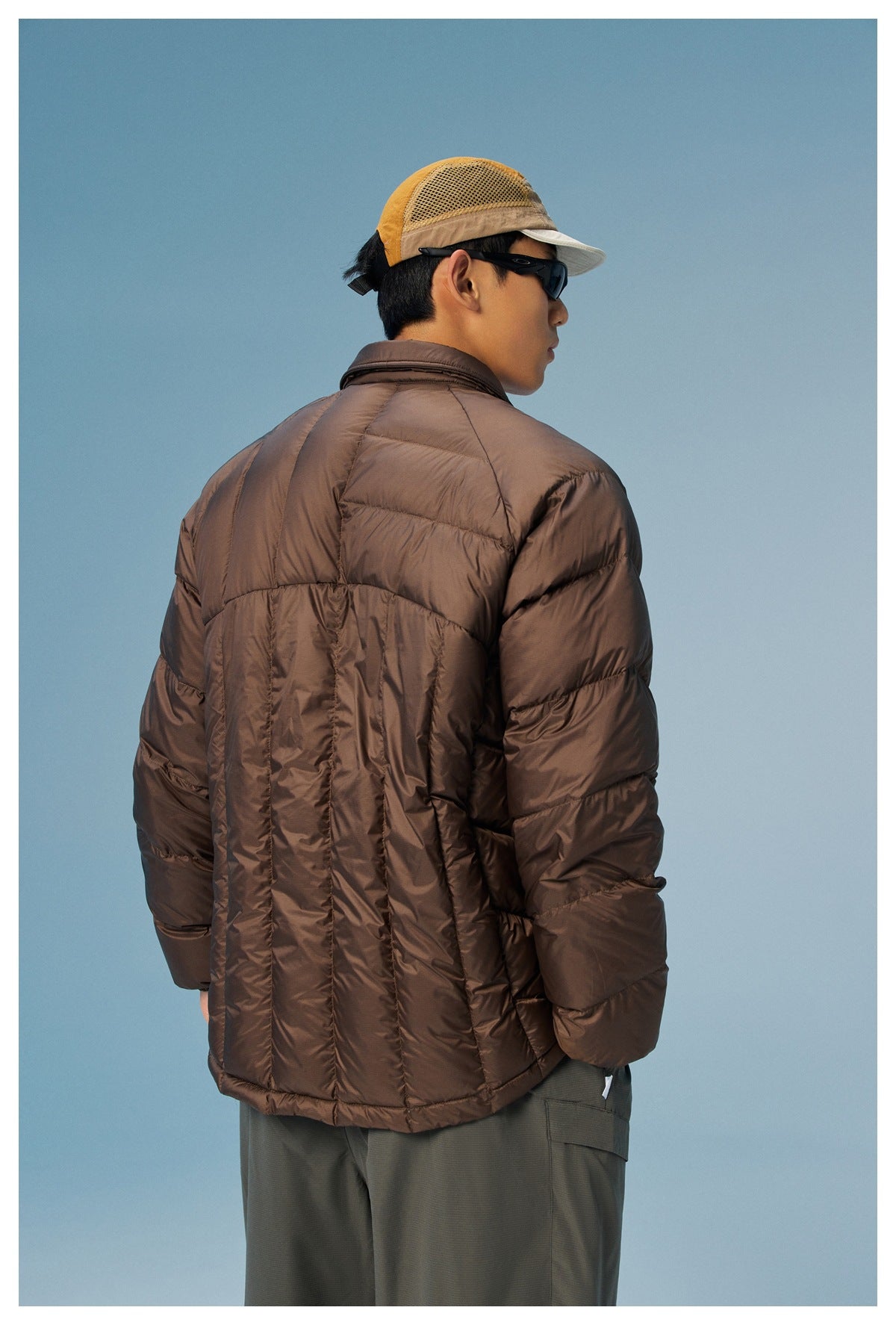 Model shown from the back wearing a dark brown quilted jacket with horizontal panels and padded sleeves.