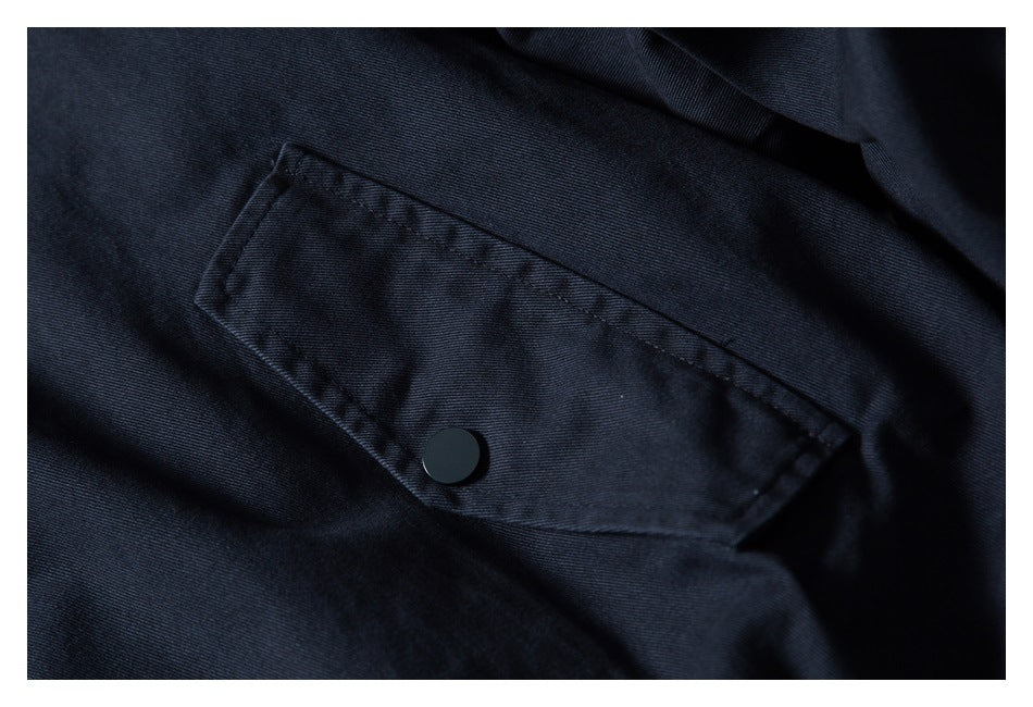 Close-up of a dark navy jacket's flap pocket with a black snap button.