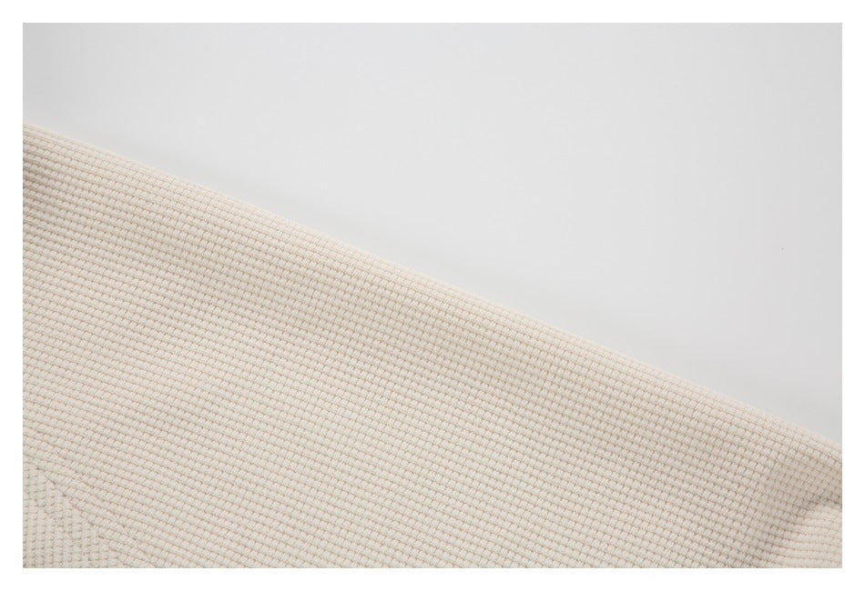 Close-up of cream textured fabric with a diagonal edge and subtle seam.