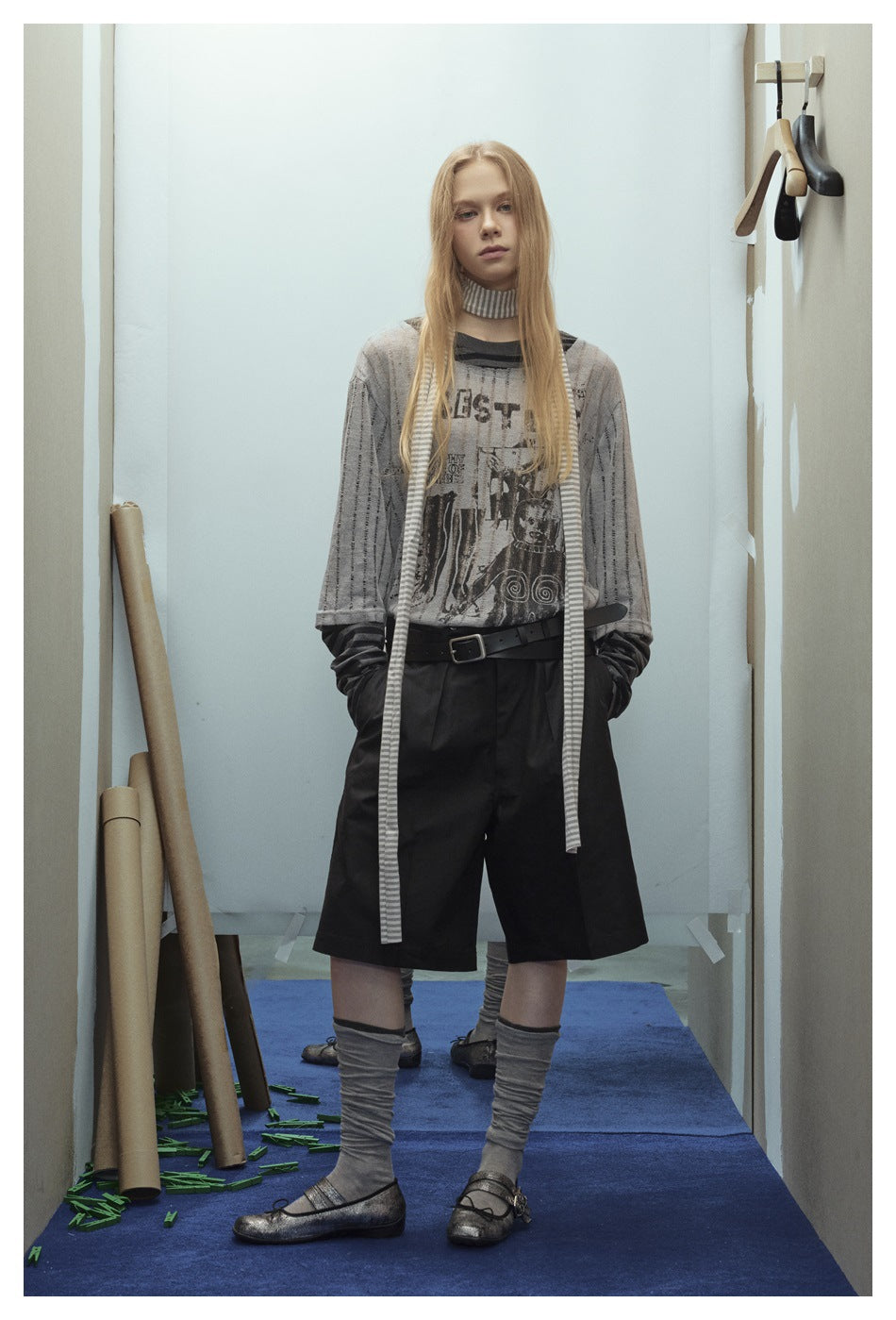 Model wearing the gray graphic layered top with a striped scarf, black belt and black shorts