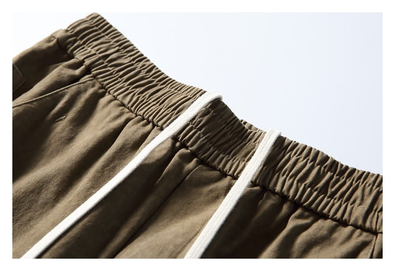 Close-up of olive-brown pants with a gathered elastic waistband and white drawstrings.