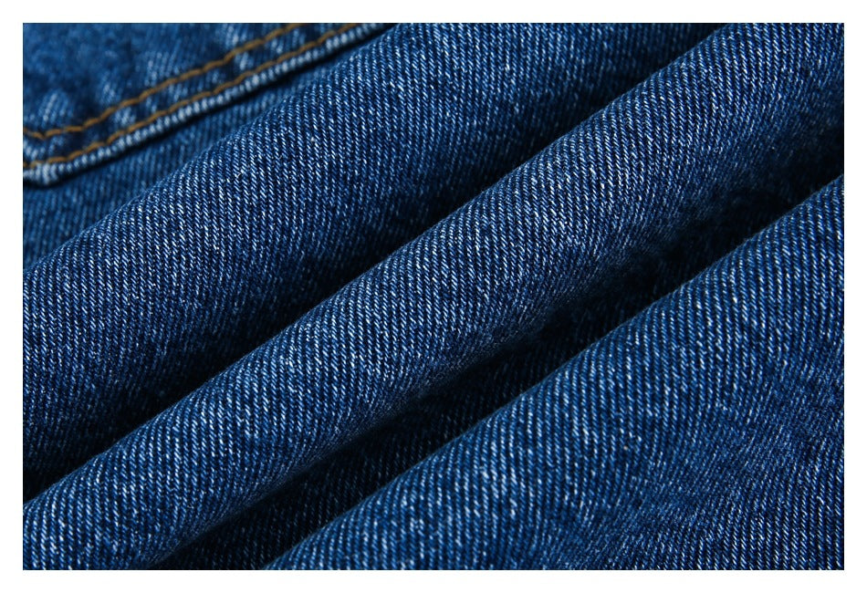 Macro close-up of dark blue denim twill texture with a folded seam at the upper left.