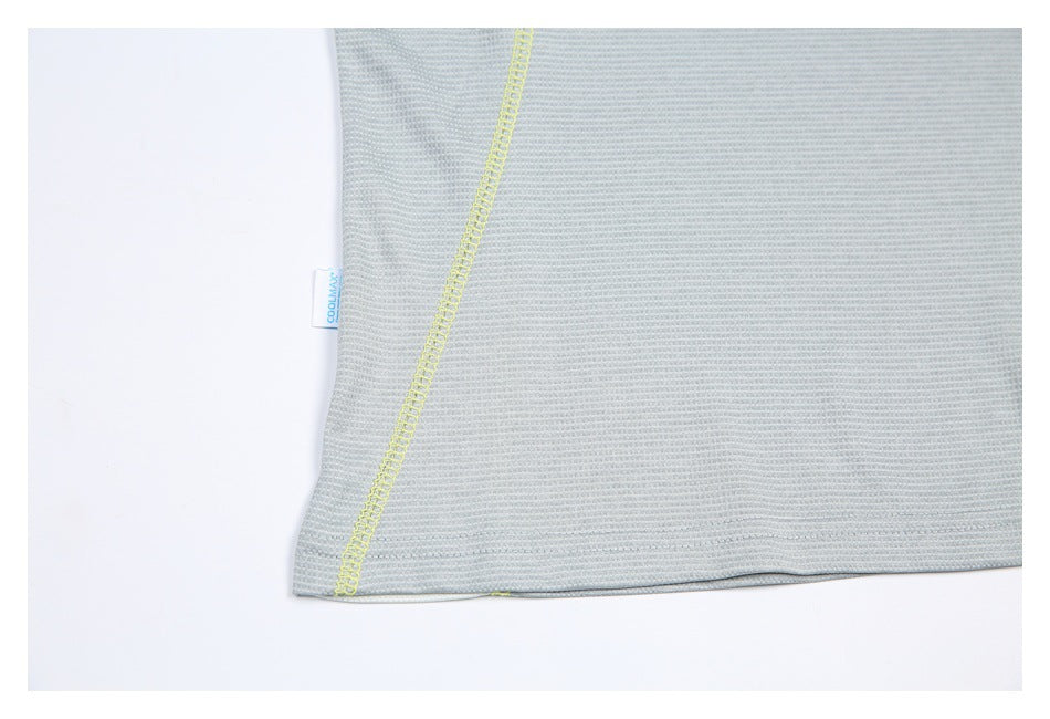 Close-up of the pale gray shirt hem with a bright yellow seam and a small side tag.