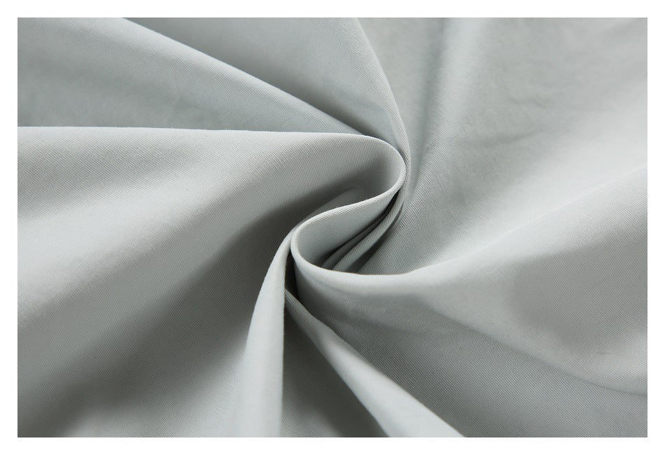 Close-up of light gray garment fabric gathered into soft folds.