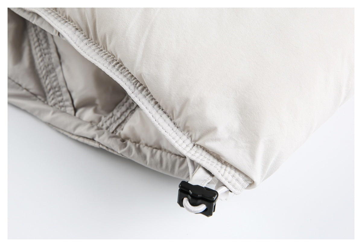 Close-up of an off-white jacket hem with reinforced stitching and a black cord adjuster.