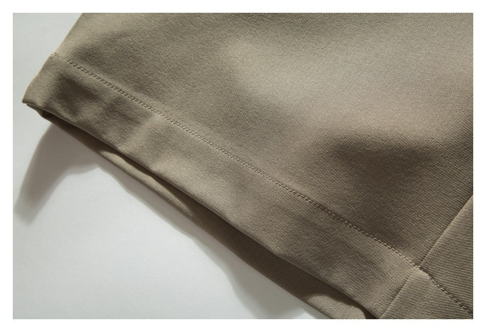 Close-up of the stitched hem on a taupe trouser leg.