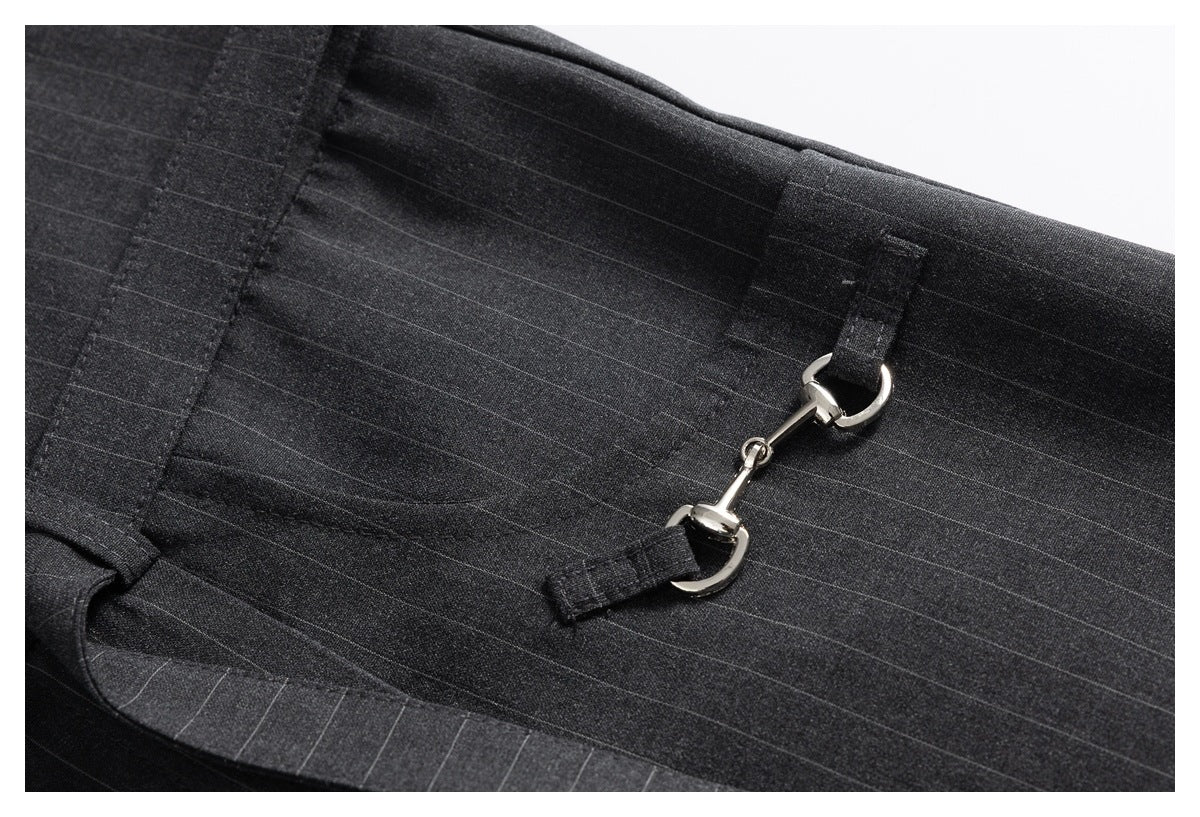 Close-up of dark charcoal pinstripe trousers with a silver hook-and-eye detail attached to fabric tabs.