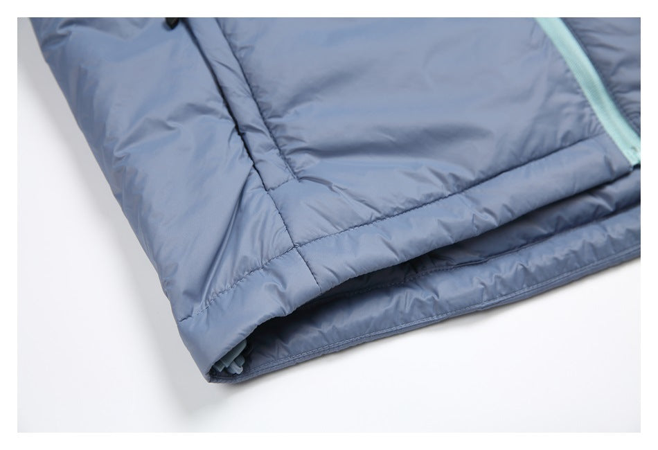 Close view of the slate-blue jacket's stitched lower hem and side seam, with part of the pale aqua zipper visible.