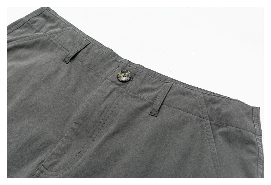 Close-up of charcoal-gray trousers showing the waistband, button, belt loops, and curved front pocket.