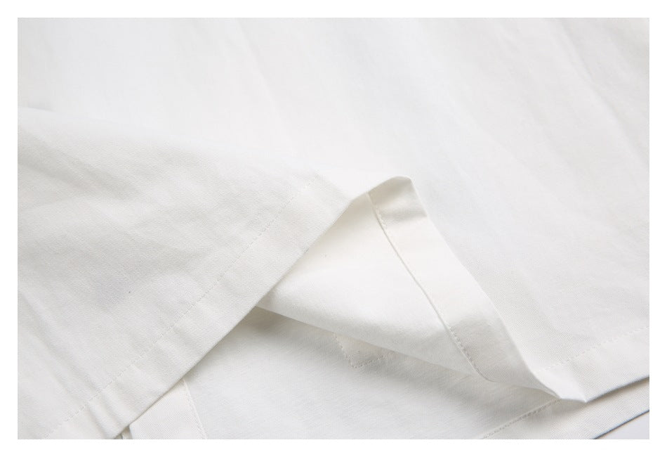 Close-up of white garment fabric folded to show a stitched seam and finished edge.
