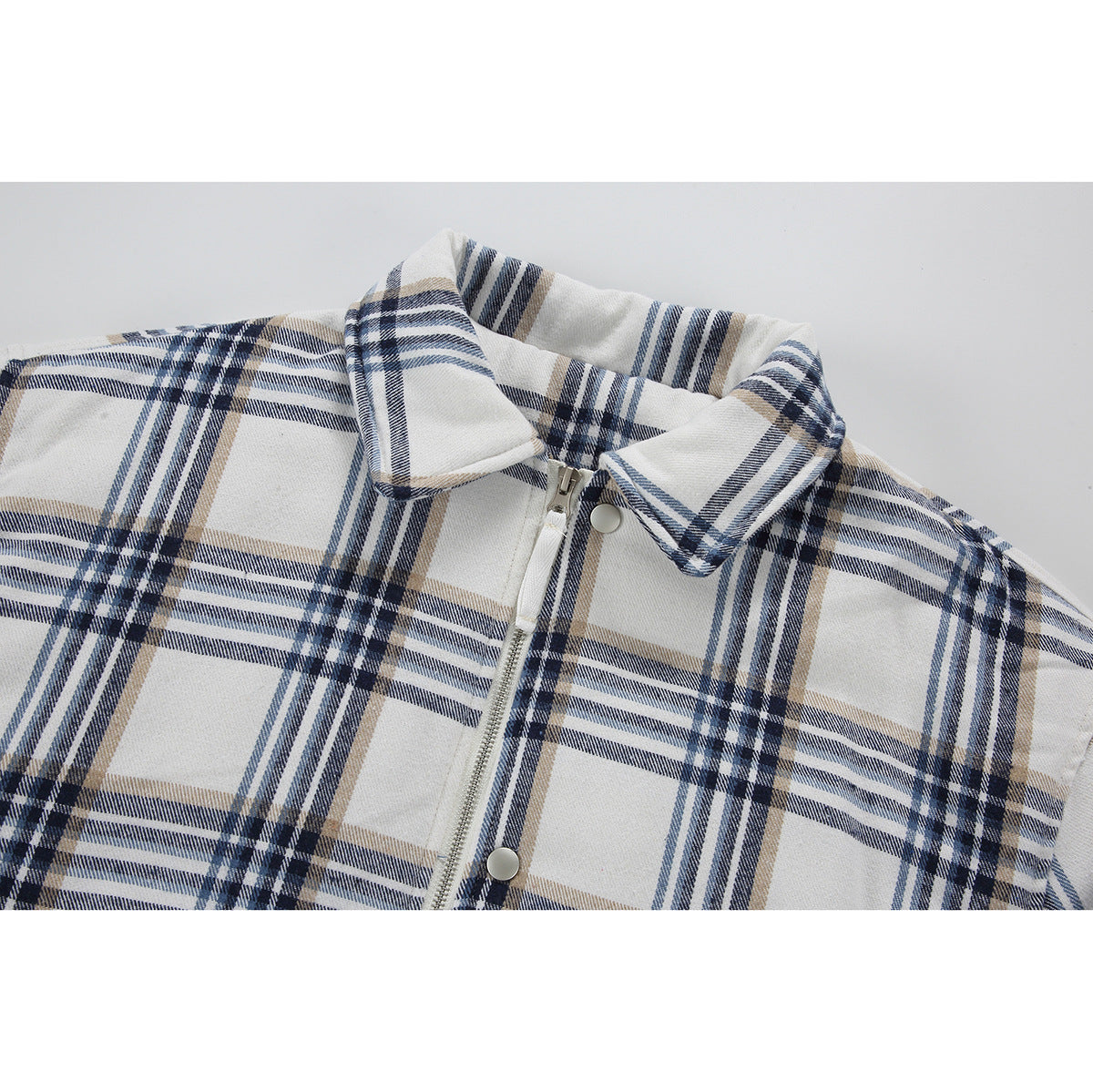 Close-up of a cream plaid jacket collar with a front zipper and snap buttons.