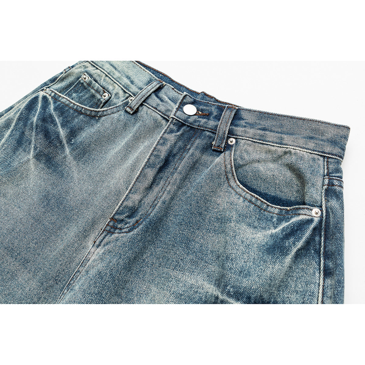Close-up of faded blue jeans showing the waistband, button, belt loops, coin pocket and front pocket.