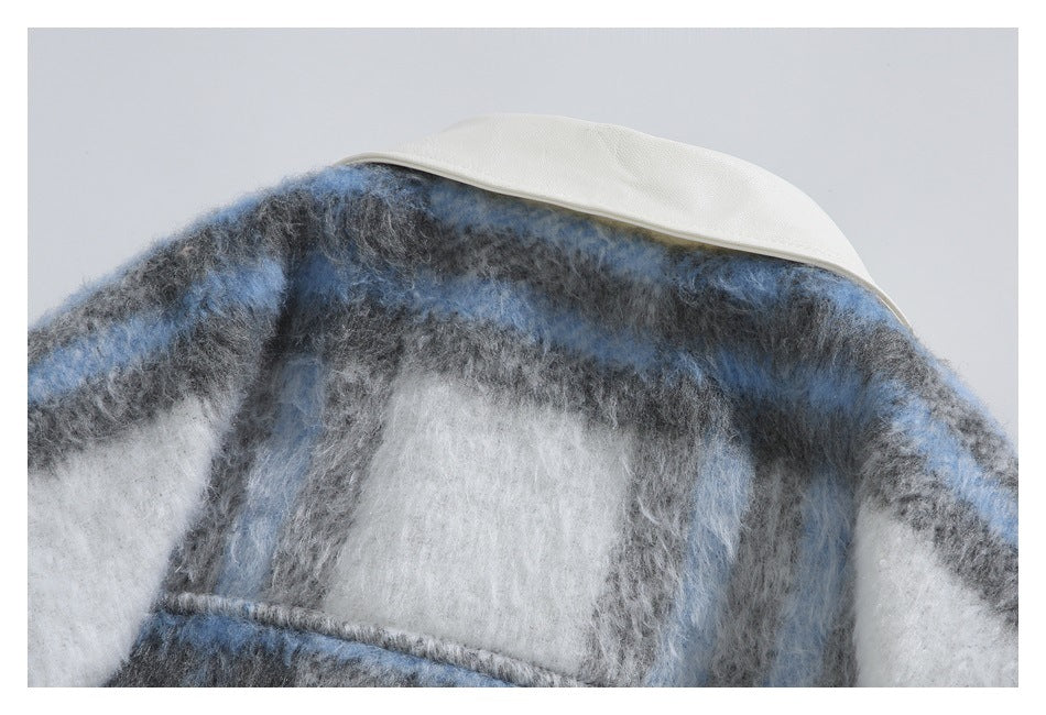 Close-up of a white collar above the fuzzy blue, gray, and white plaid fabric.