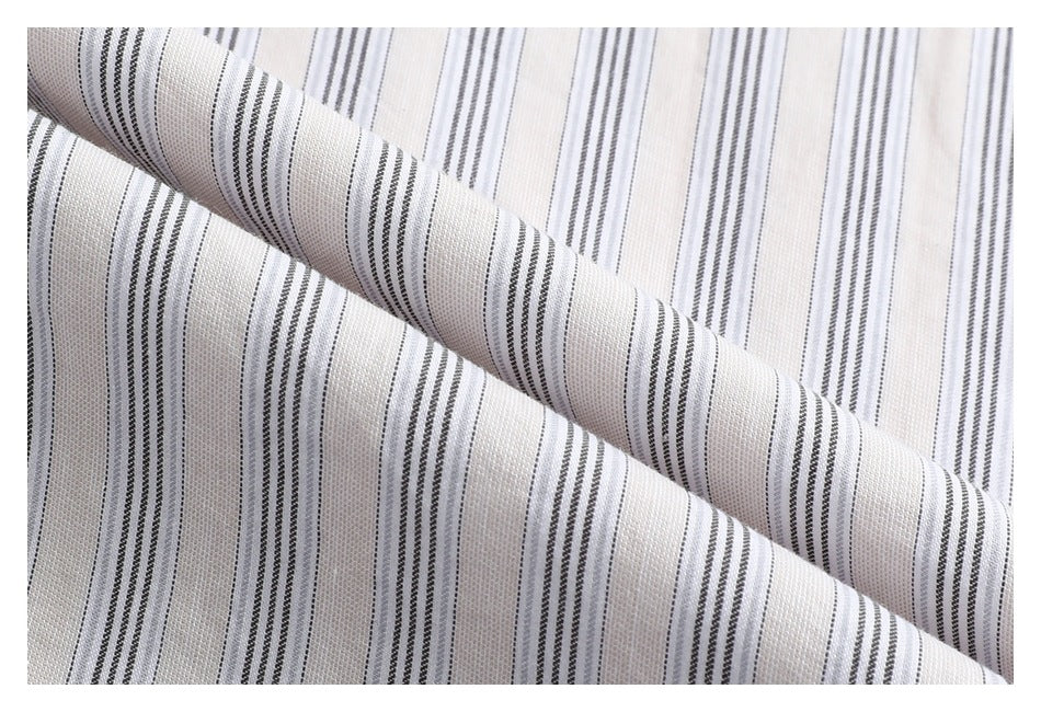 Close-up of white fabric with narrow gray stripes, folded diagonally to show the pattern.