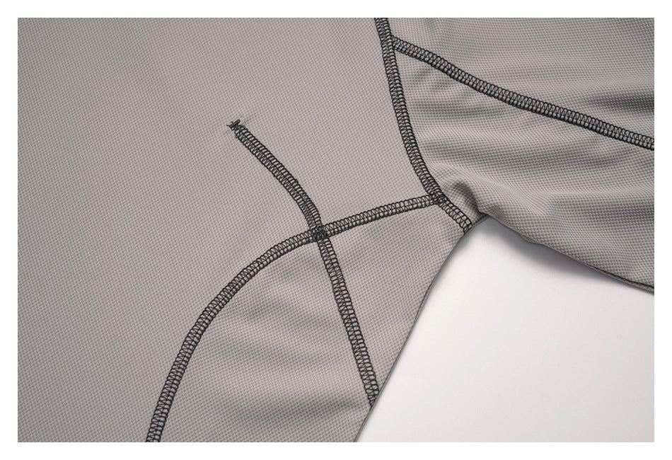 Close-up of curved panel seams and dark overlock stitching on the gray top.