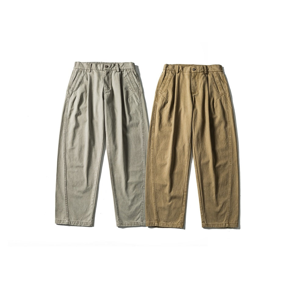 Front view of two pairs of pleated trousers, one light gray and one tan, laid flat side by side.