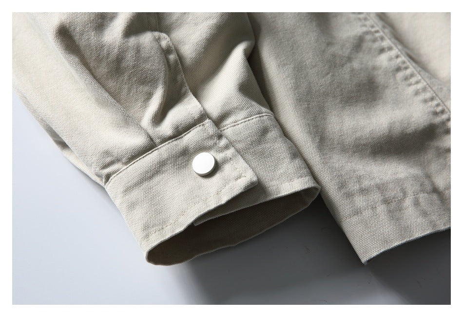Close-up of a wide light beige cuff with a round silver snap button.
