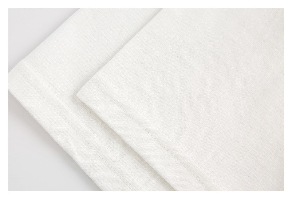Close-up of a white garment with a folded, stitched hem.