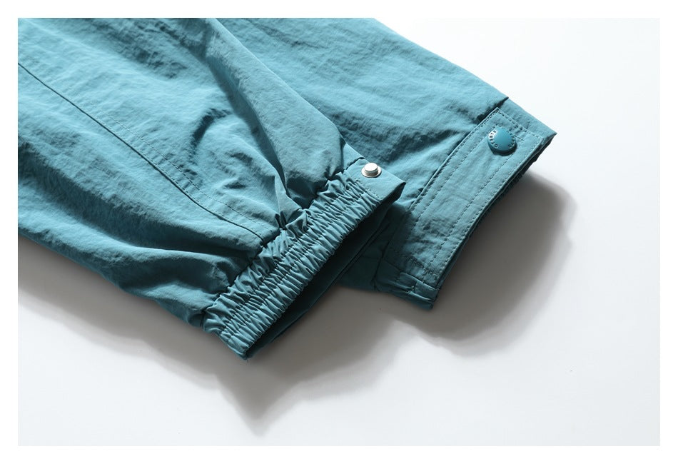 Close-up of a teal jacket sleeve with a gathered elastic section and snap-adjustable cuff tab.