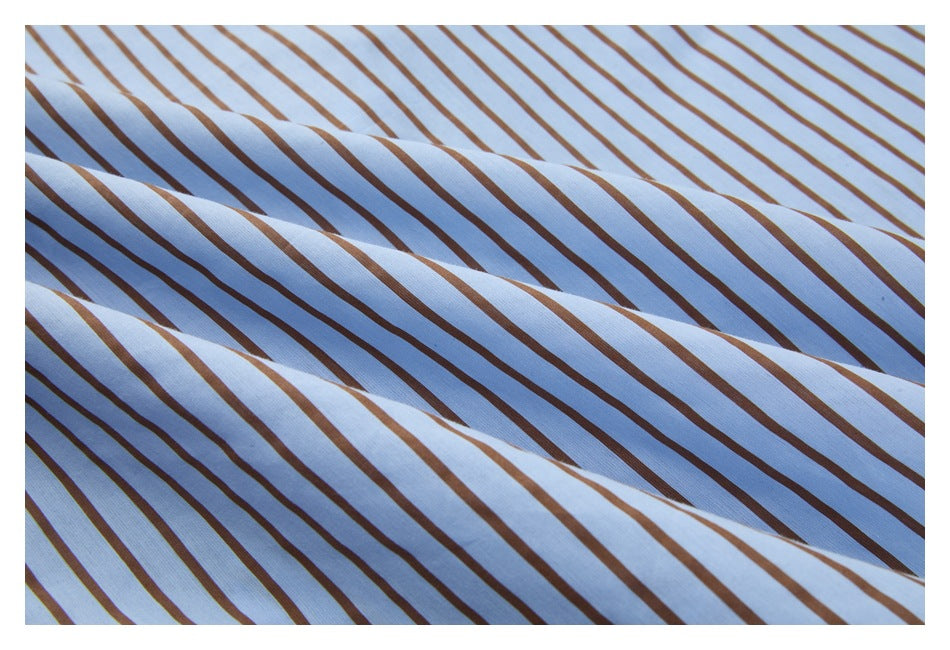 Close-up of light blue and white fabric with narrow brown diagonal stripes, softly draped in folds.