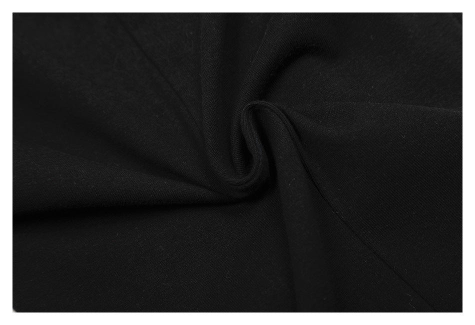 Close-up of black garment fabric gathered into a soft twist, showing its folds and surface.