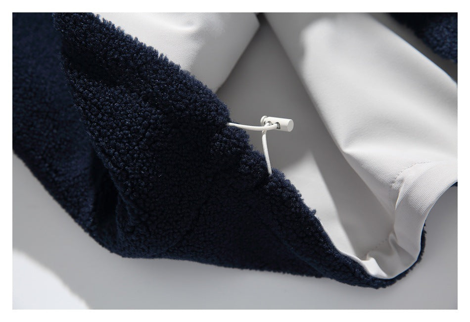 Close-up of a white drawcord and toggle at the hem of a navy fleece jacket with white lining.