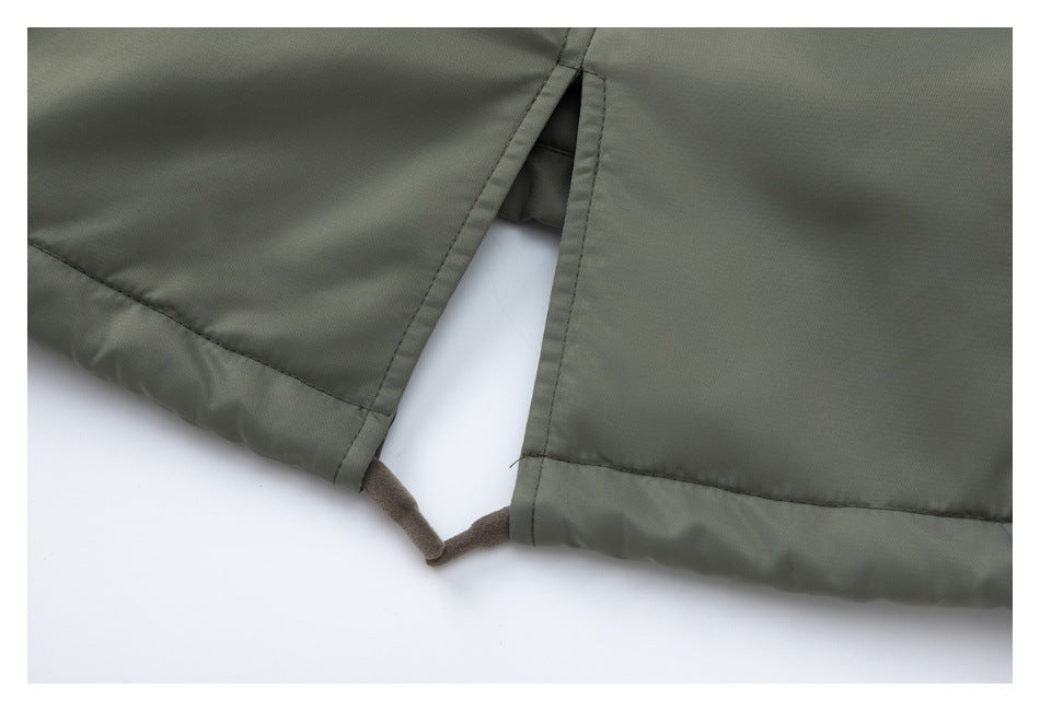 Close-up of olive-gray garment fabric with stitched edges and a small opening at the seam.