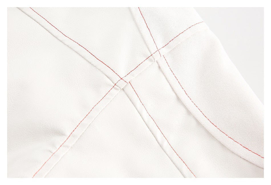 Close-up of intersecting seams and red topstitching on white jacket fabric.