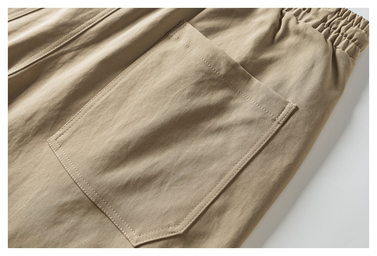Close-up of a large stitched patch pocket on tan trousers.