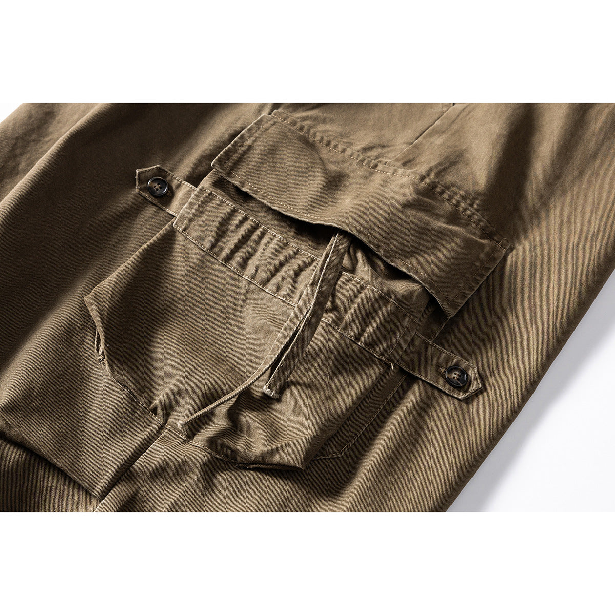 Close-up of khaki-brown cargo shorts showing a large flap pocket and adjustable buttoned straps.