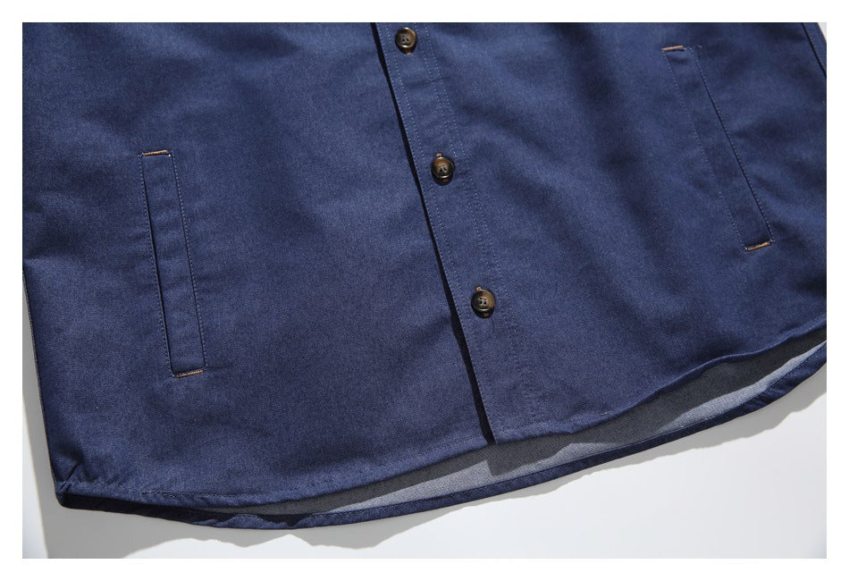 Close-up of the navy shirt’s lower front, with two slim pockets, buttons and a curved hem.