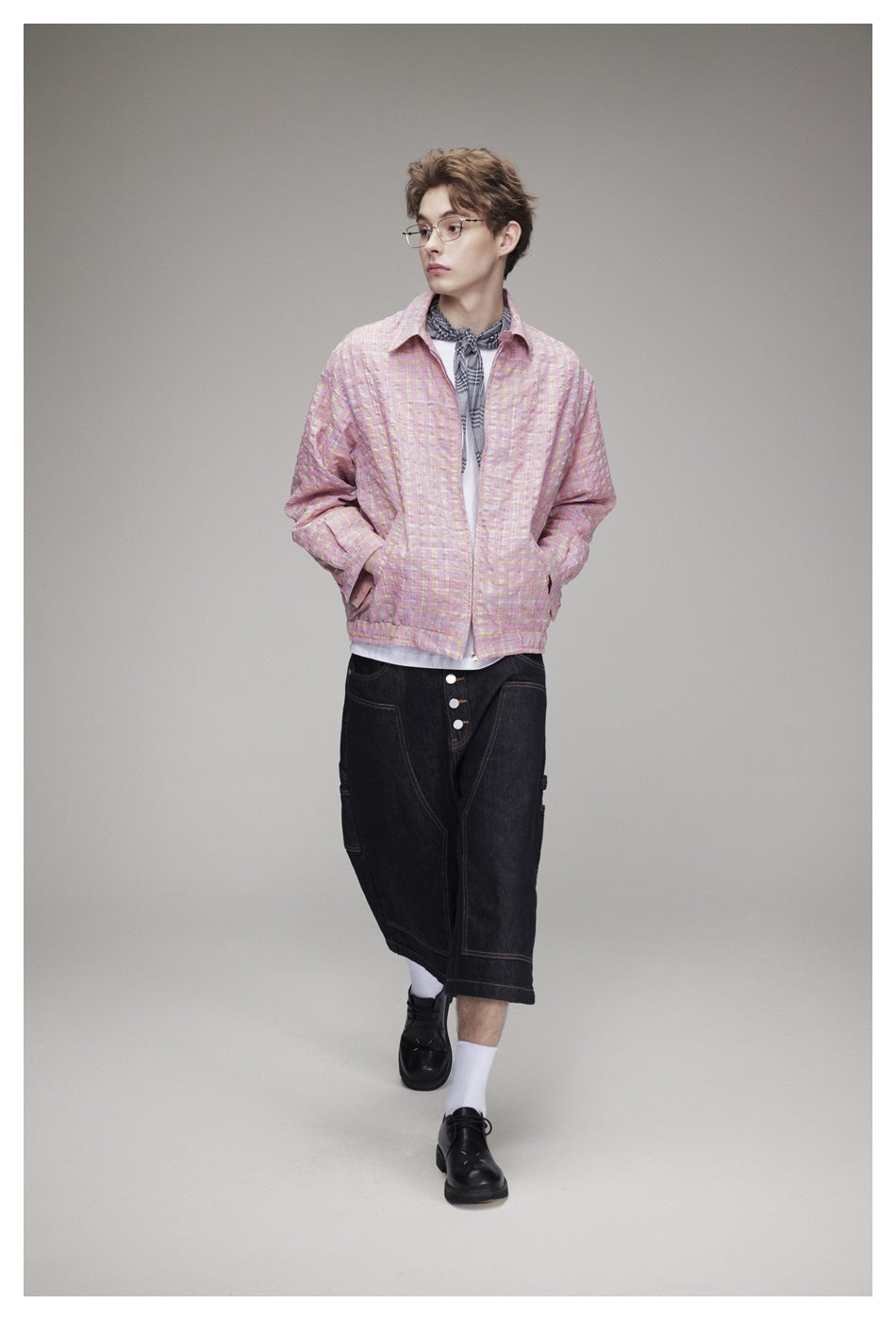 Full-length model wearing a pink plaid jacket, white shirt, dark denim knee-length shorts, white socks, and black shoes.