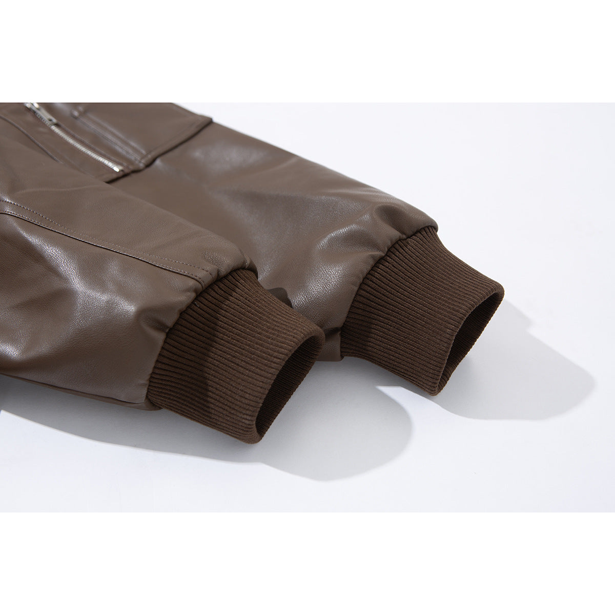 Close-up of brown jacket sleeves with dark ribbed cuffs and stitched seams.