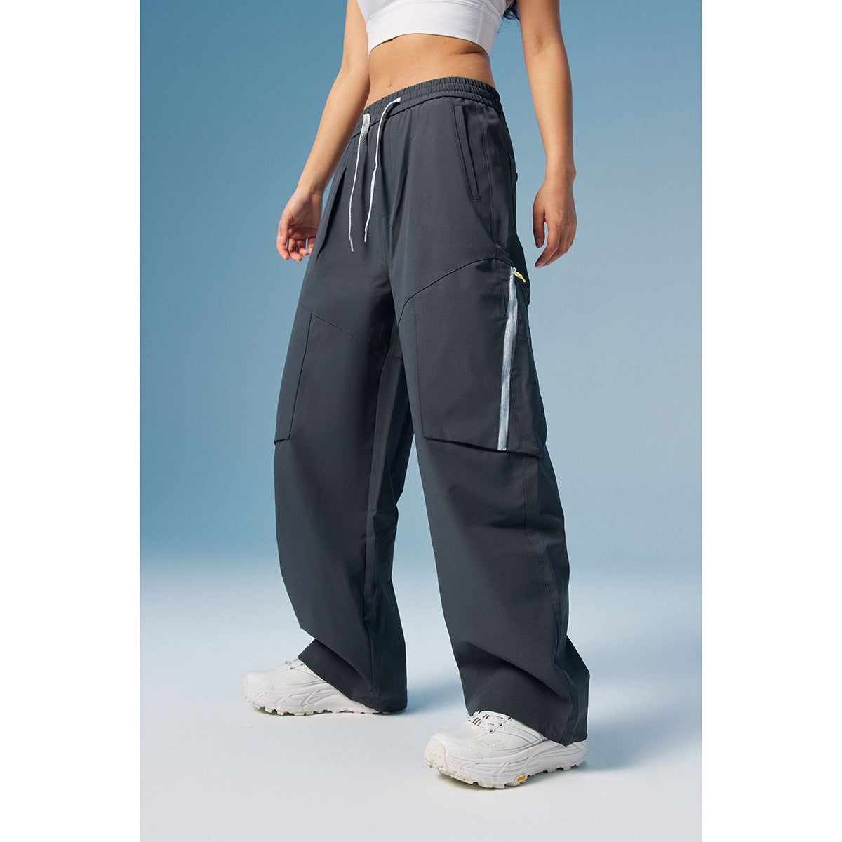 Model wearing charcoal wide-leg cargo pants with a drawstring waist and pale trim on the side pocket.