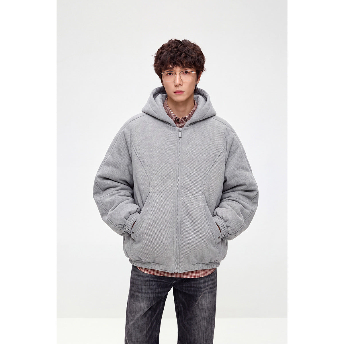 Model wearing a light gray hooded zip-up jacket with curved front pockets and gathered cuffs.