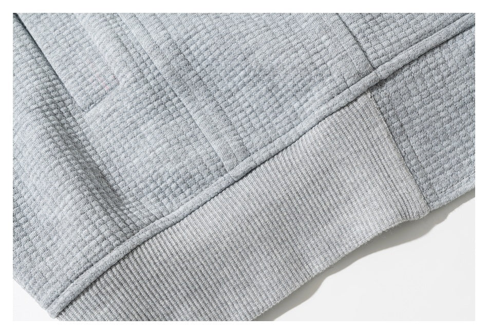 Close-up of the gray sweatshirt's textured fabric and ribbed hem.