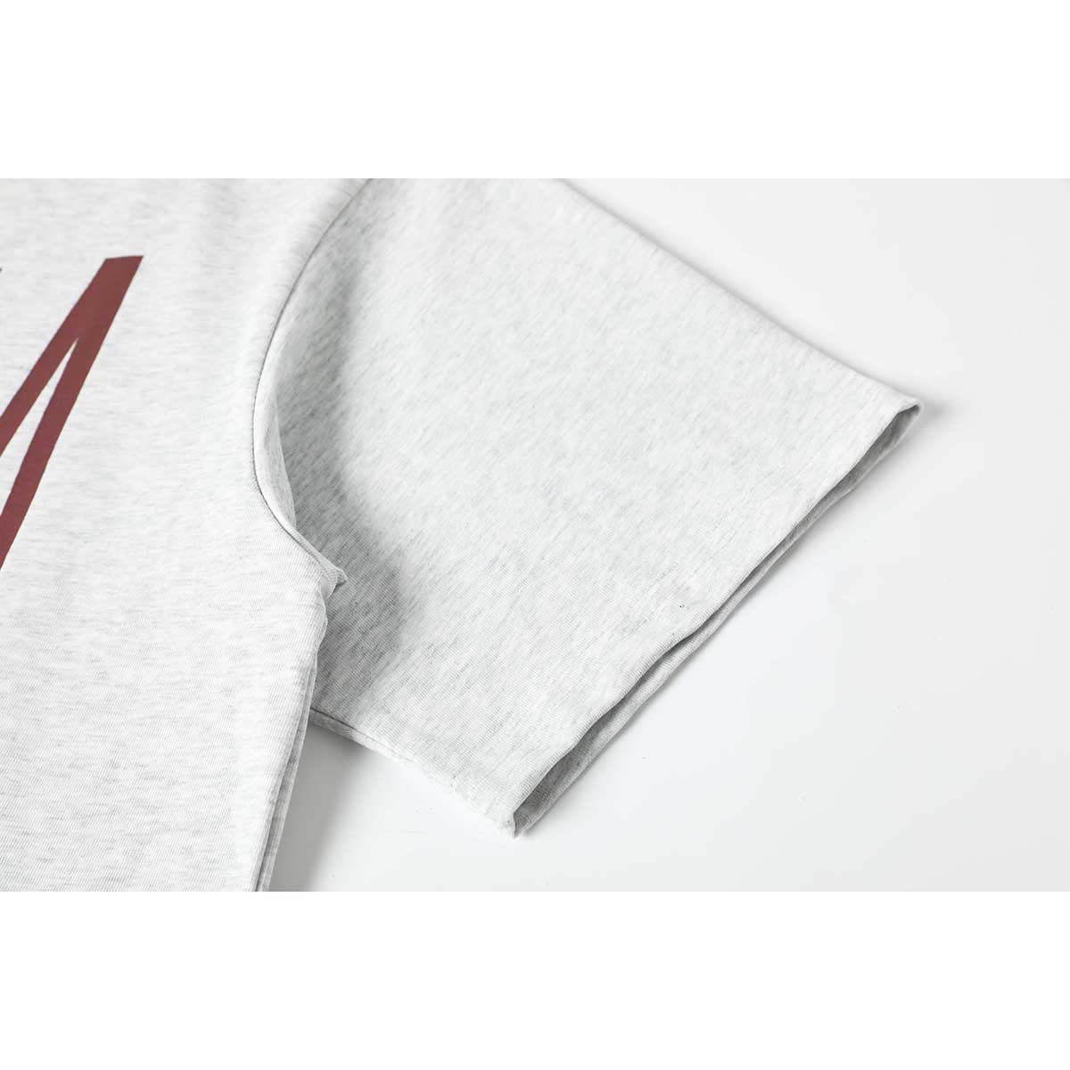 Close-up of a light gray melange T-shirt sleeve and a partial burgundy chest print.