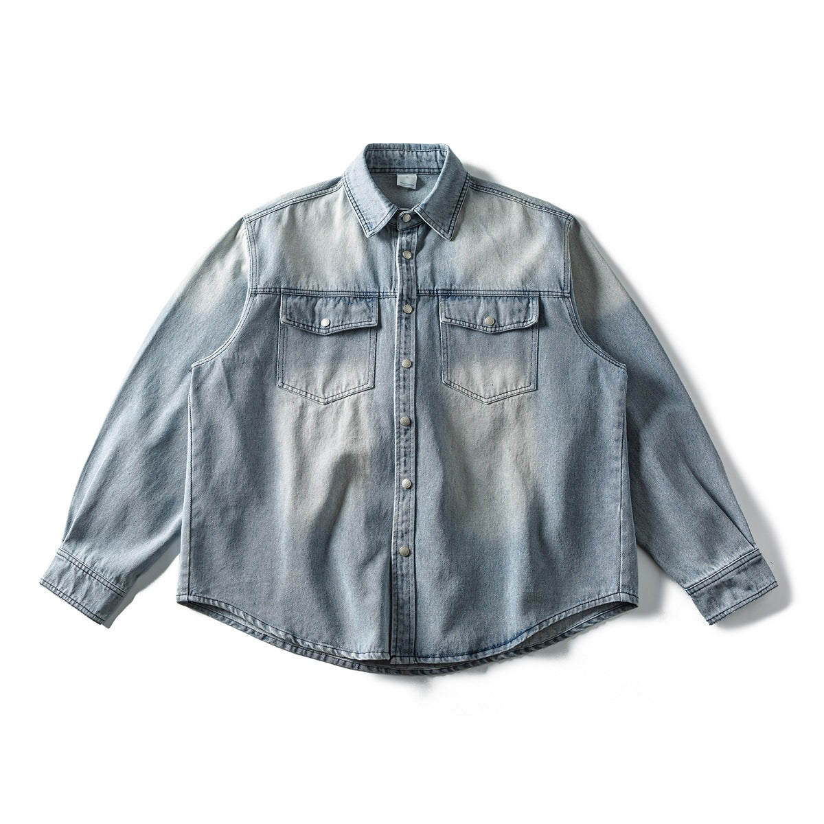 Light blue washed denim long-sleeve shirt with snap front, two flap chest pockets and curved hem, laid flat