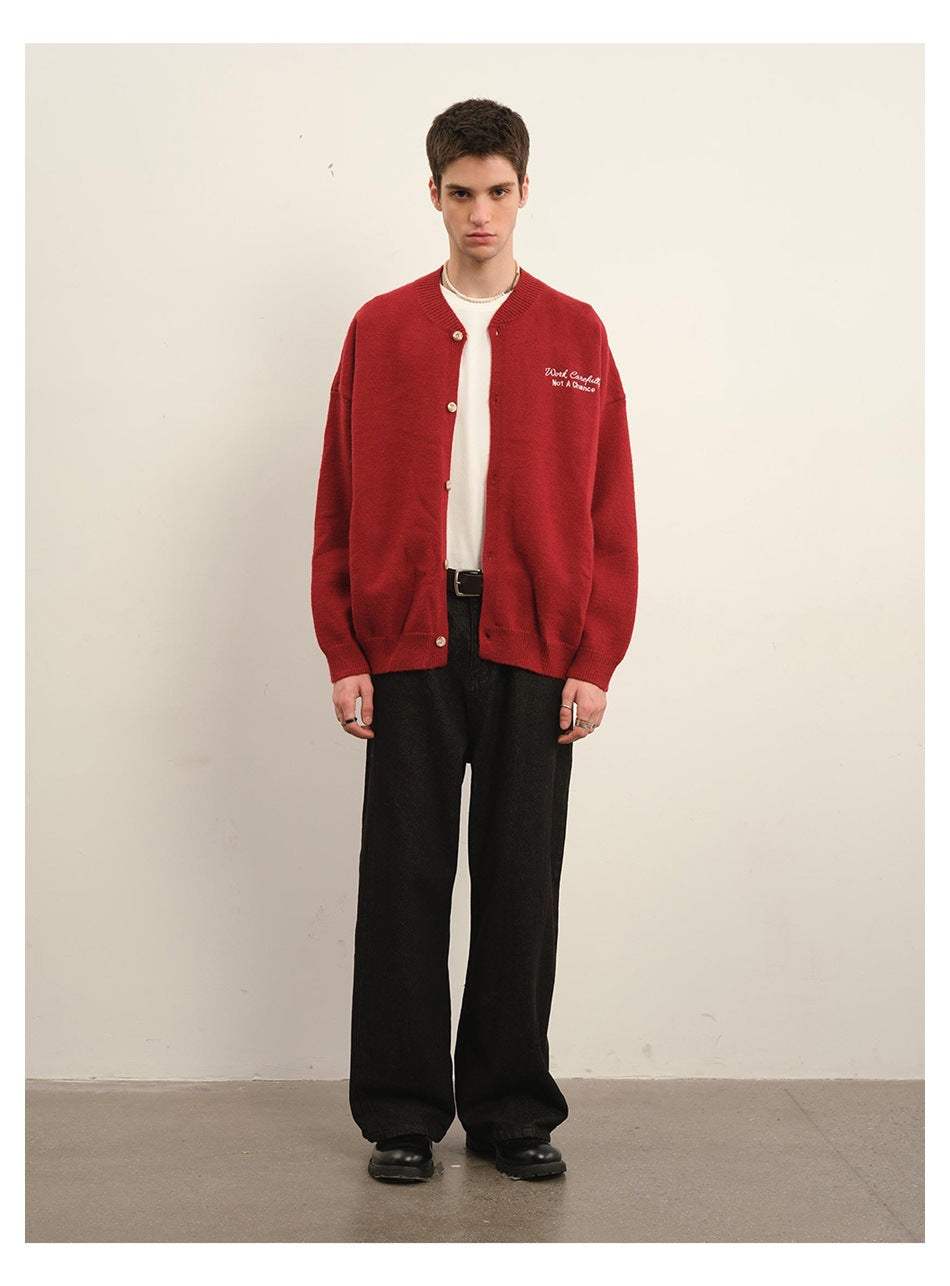 Front view of a model wearing a red button-front cardigan with white chest embroidery and black trousers.
