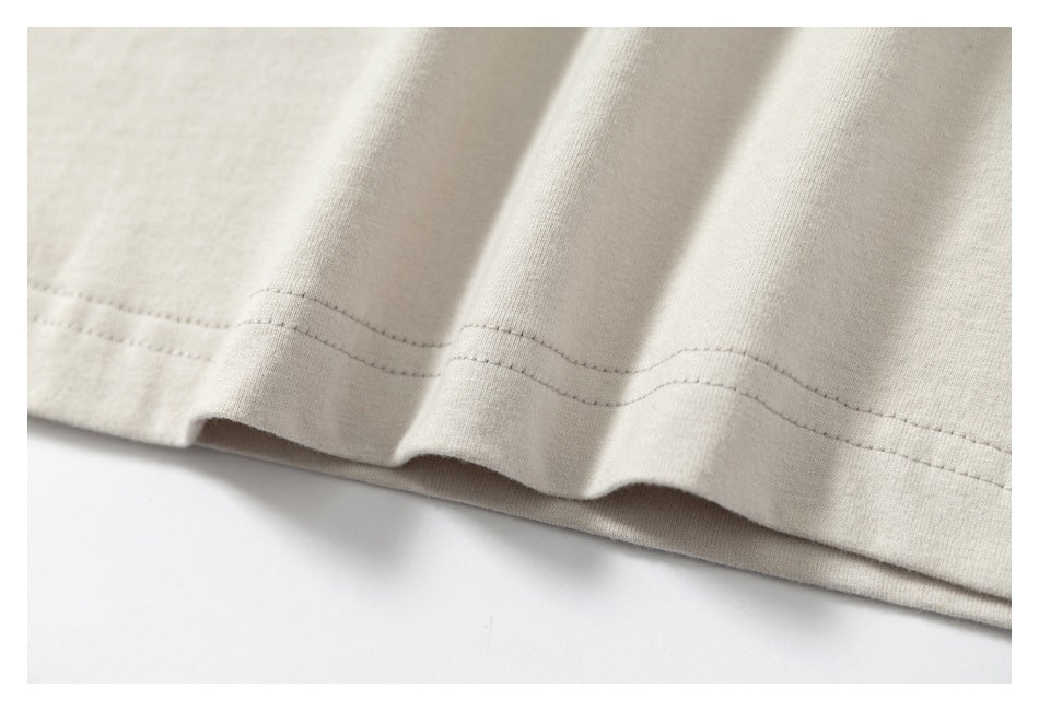 Close-up of the ivory garment's stitched hem and softly draped fabric.
