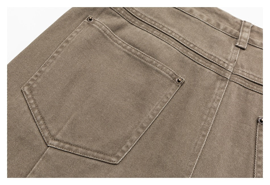 Close-up of a taupe-gray jeans back pocket with contrast stitching and metal rivets.
