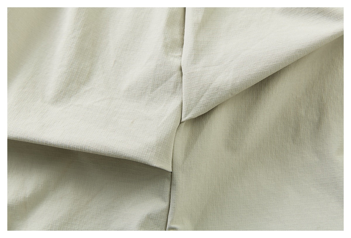 Close-up of pale khaki garment construction with overlapping panels and a vertical seam.