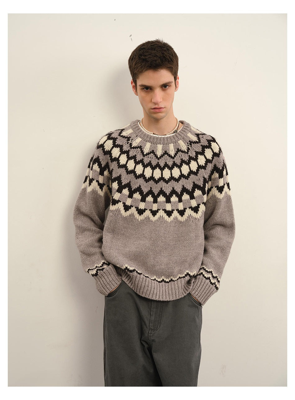 Closer front view of a model wearing a taupe gray sweater with a black and cream geometric yoke.