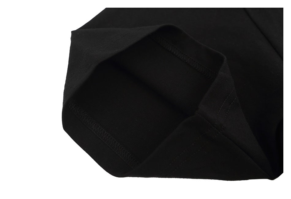 Close-up of the black T-shirt's sleeve opening and overlock stitching.