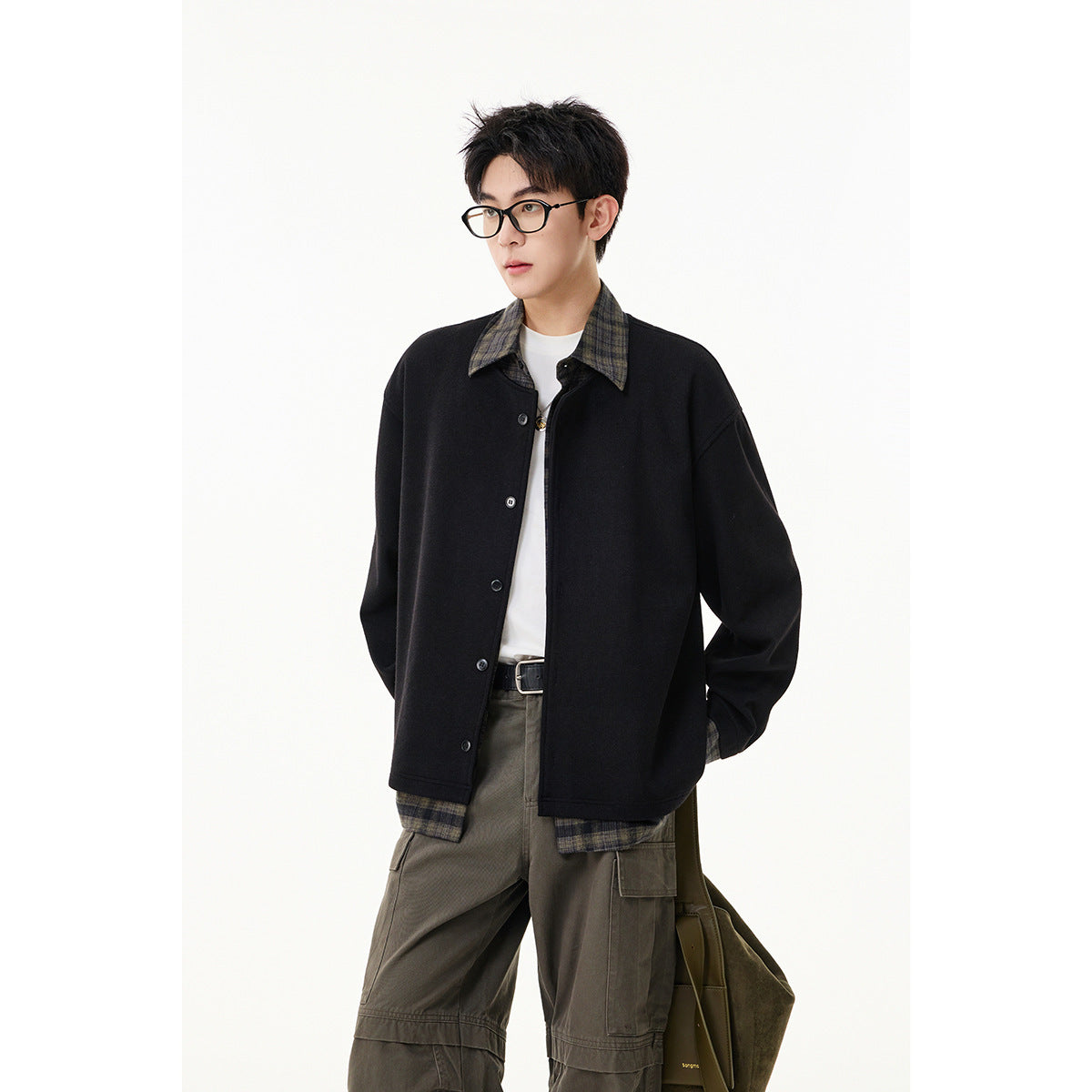 Model wearing a black button jacket with a plaid collar and cuffs over a white shirt.